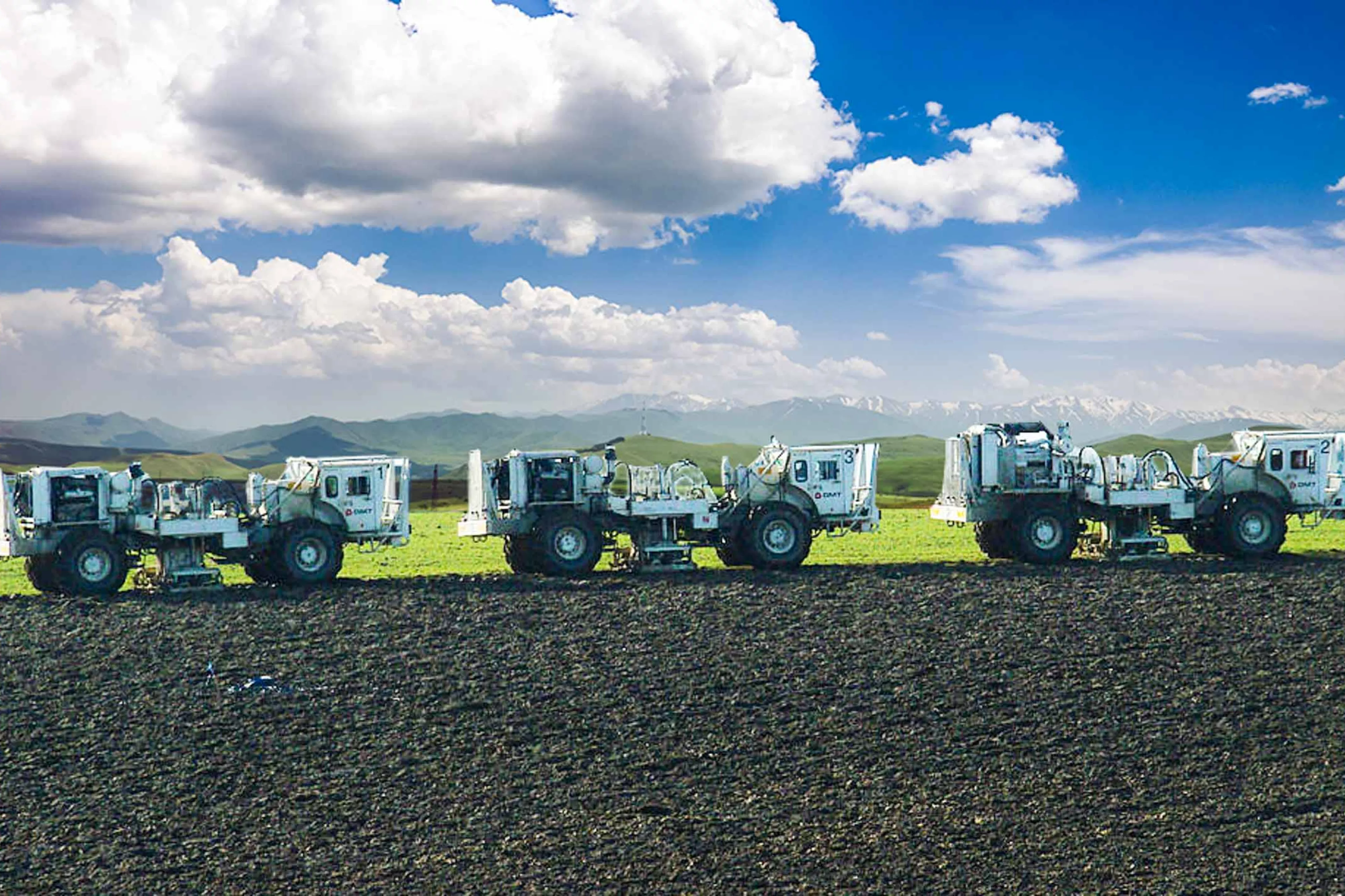 Three vibraseis trucks on edge of field